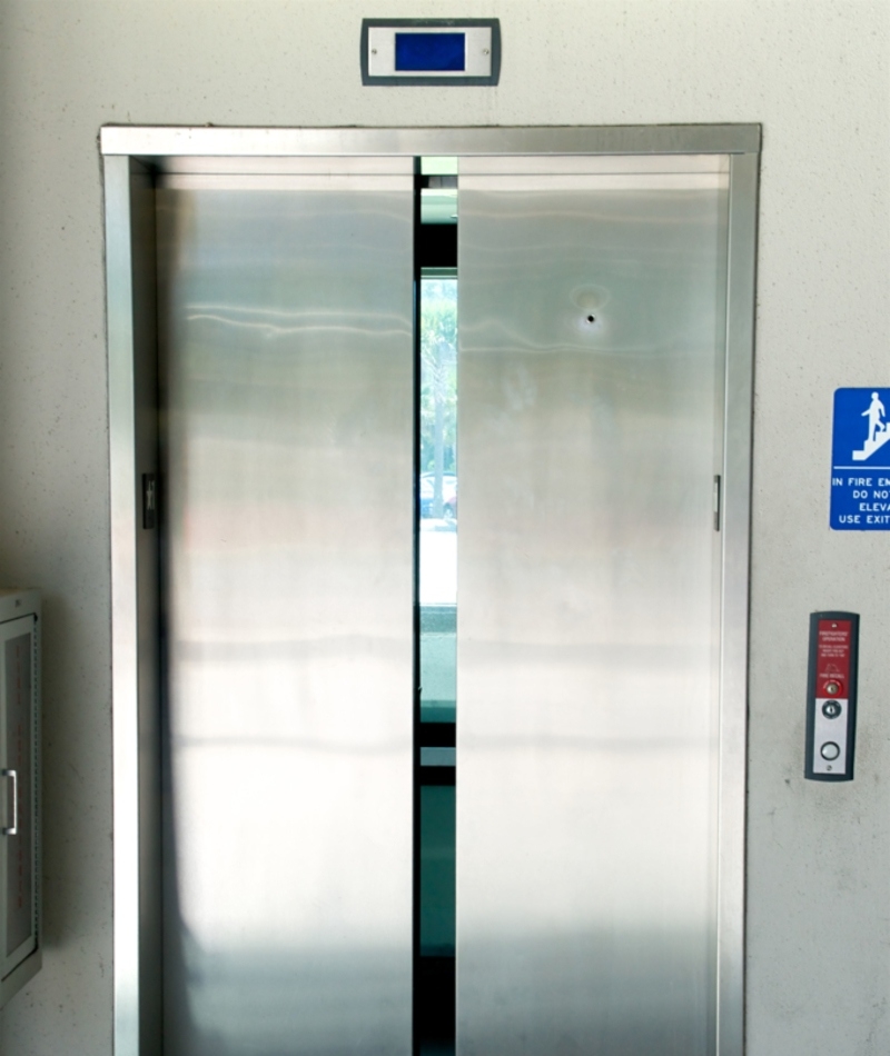 Un agujero en las puertas del ascensor | Alamy Stock Photo